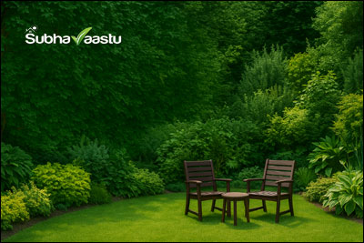 Peaceful garden sitting area with two chairs and a small table surrounded by lush green plants and trees in a serene backyard setting